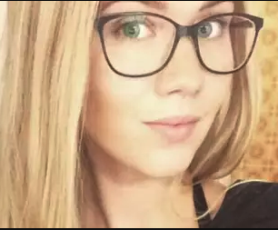 Nærbilde av ung kvinne med blondt hår og briller som ser mot kamera.