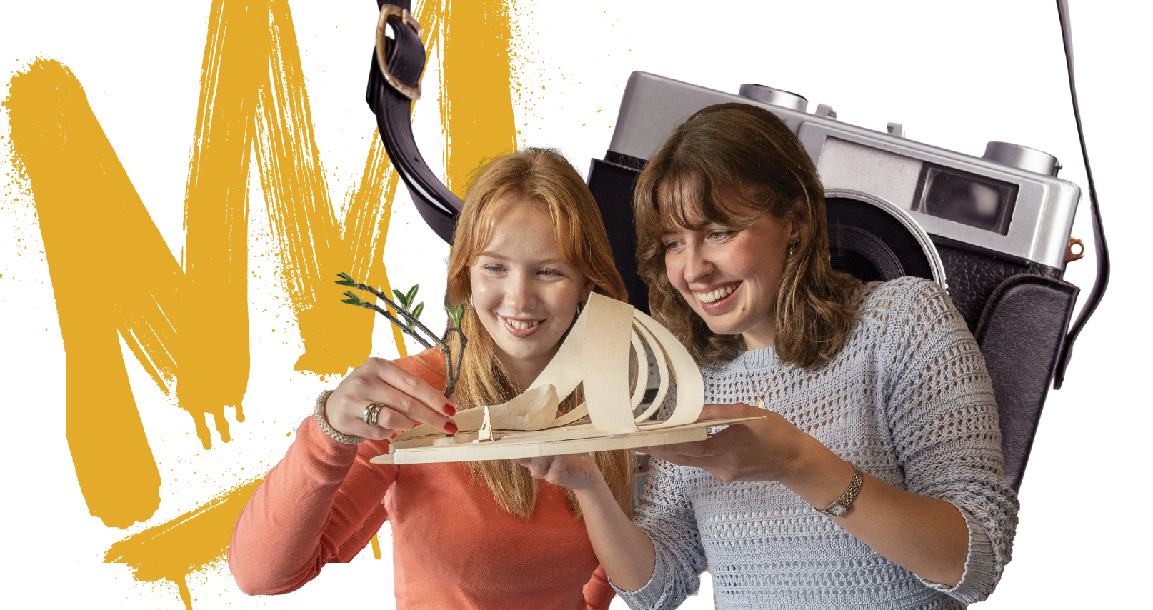 To unge kvinner smiler mens de holder og ser på en arkitekturmodell med buede former og små trær.