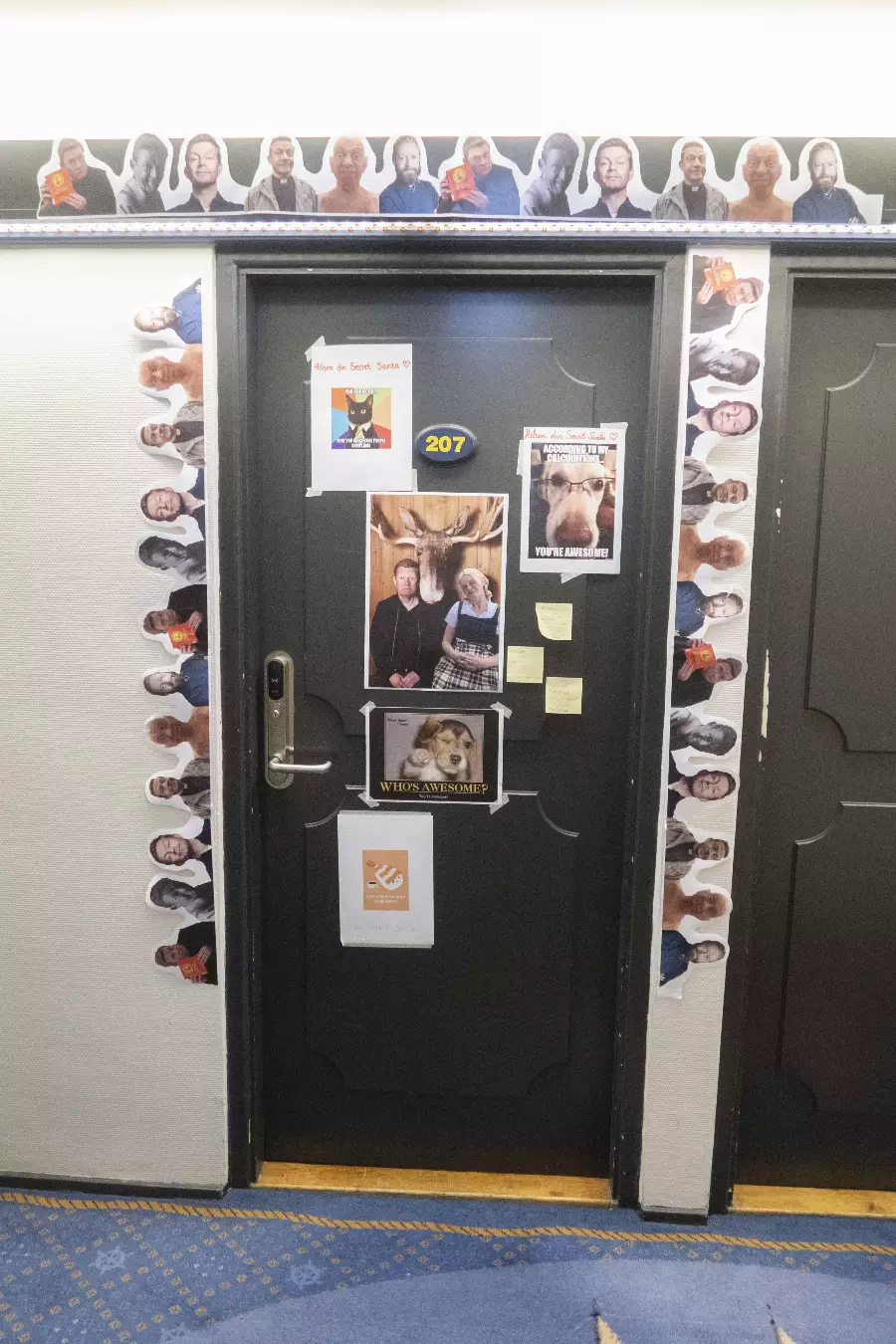 Dør nummer 207 dekorert med morsomme bilder av mennesker, dyr og cut-outs langs dørkarmen og bildene festet på døren.