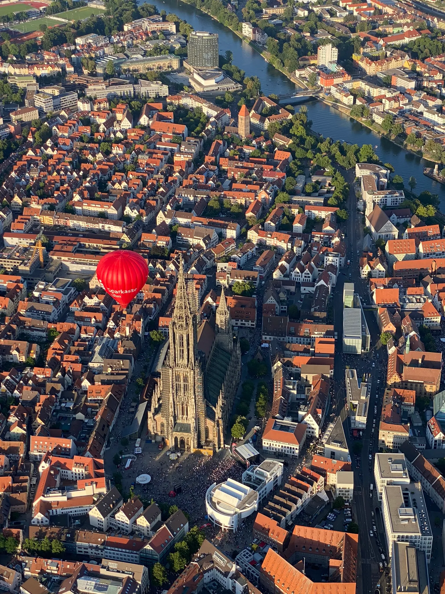 Luftaufnahme der Stadt Ulm mit dem Ulmer Münster und einem roten Heißluftballon mit der Aufschrift Sparkasse.
