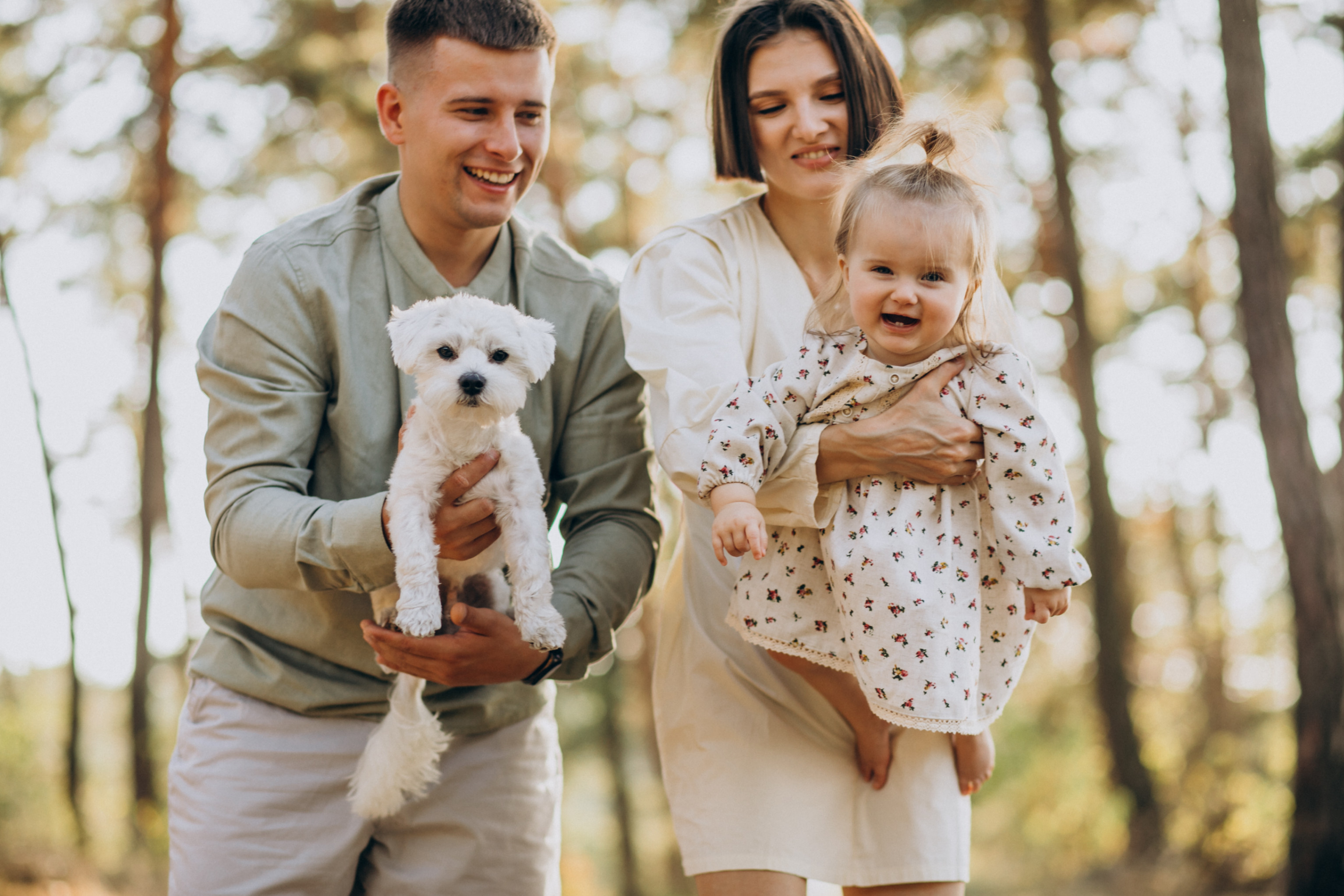 Un jeune couple tenant une petite fille dans es bras fait une promenade dans la forêt