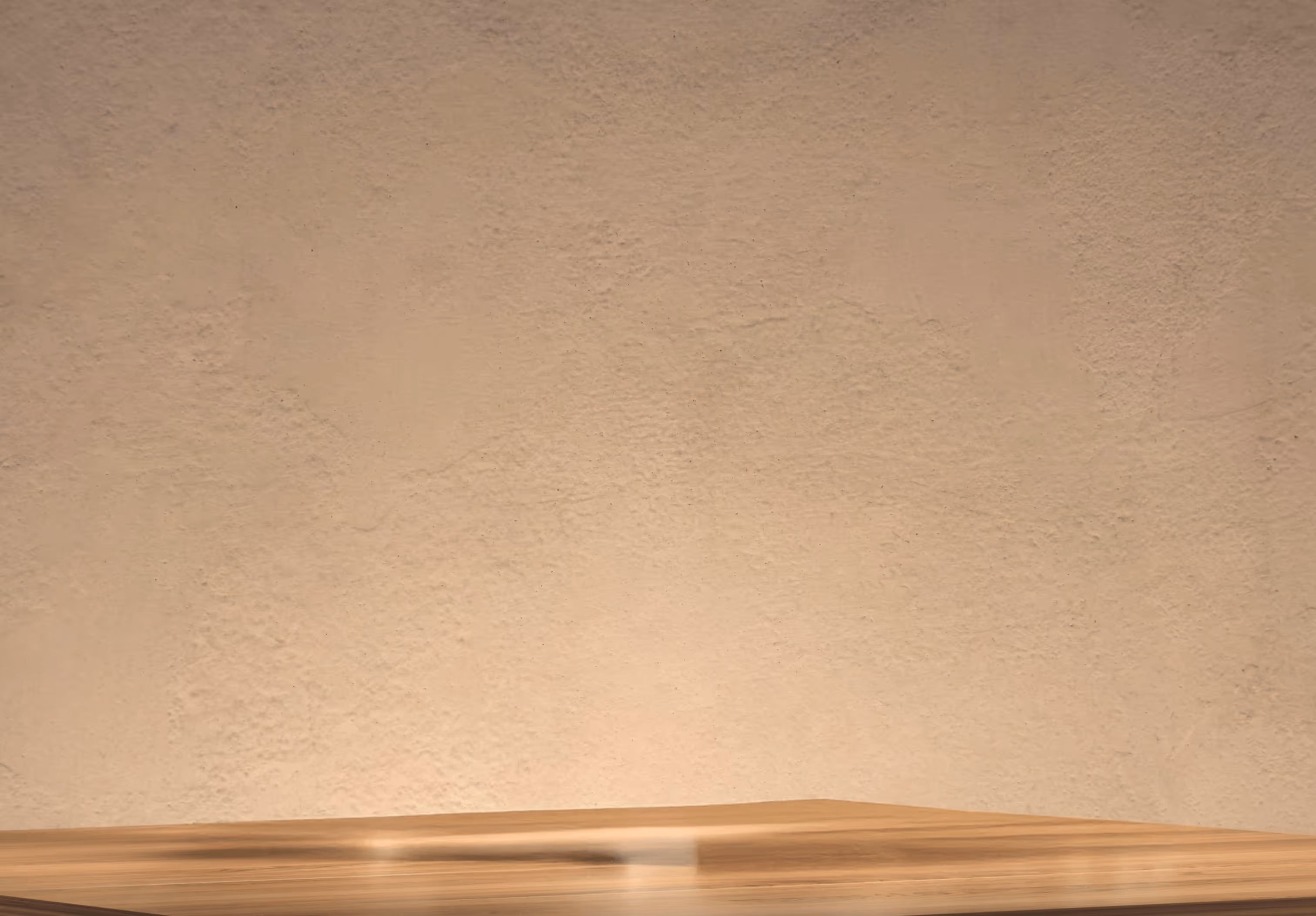 Empty wooden table with a textured beige wall background and soft lighting.