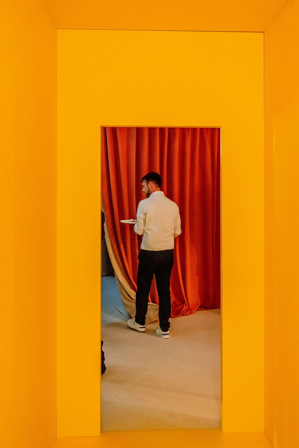 Smiling woman with braided hair wearing a black dress with a cutout midsection and raising both hands.