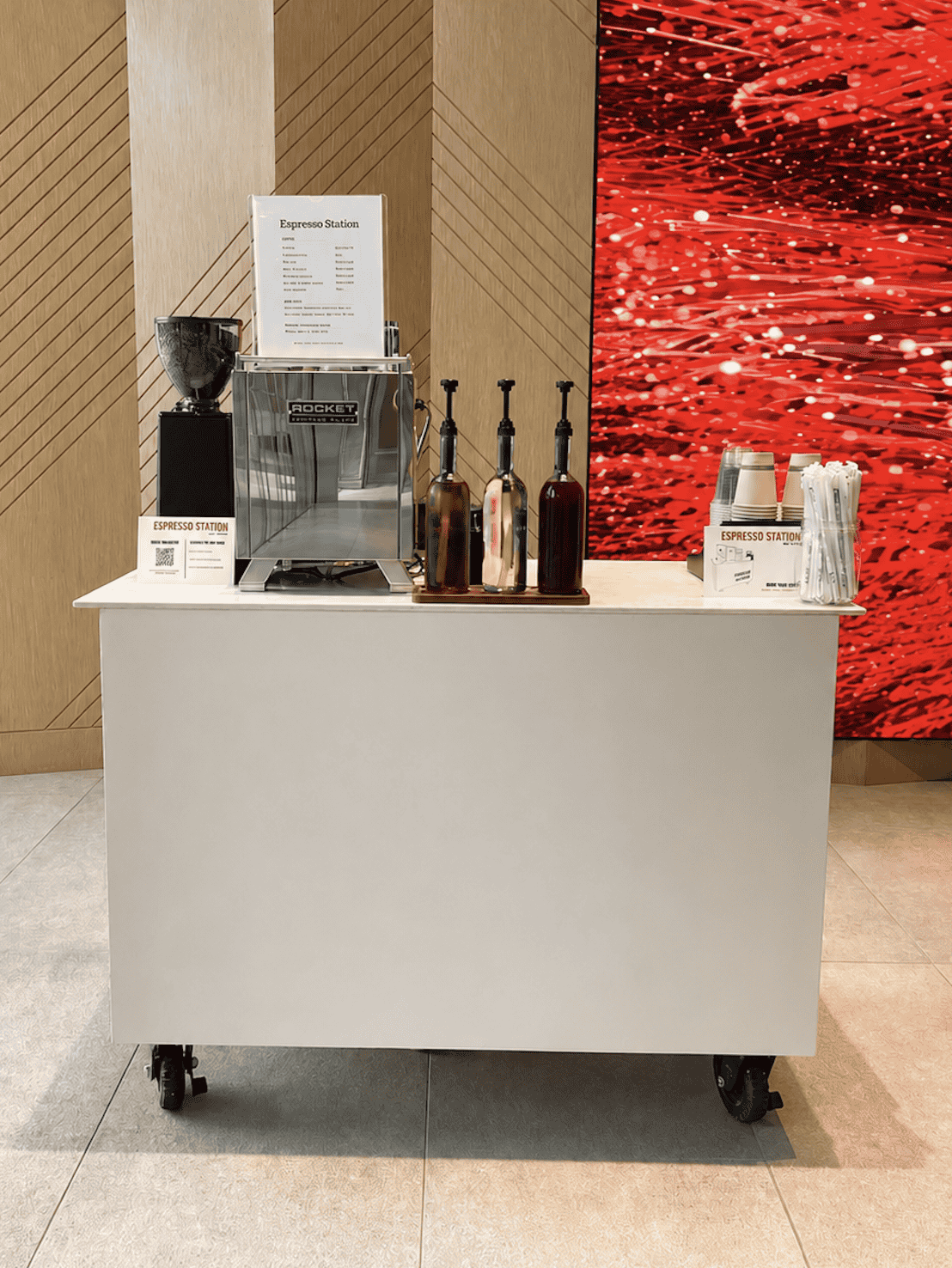 Espresso Station coffee cart beside a large red LED video wall in a corporate lobby