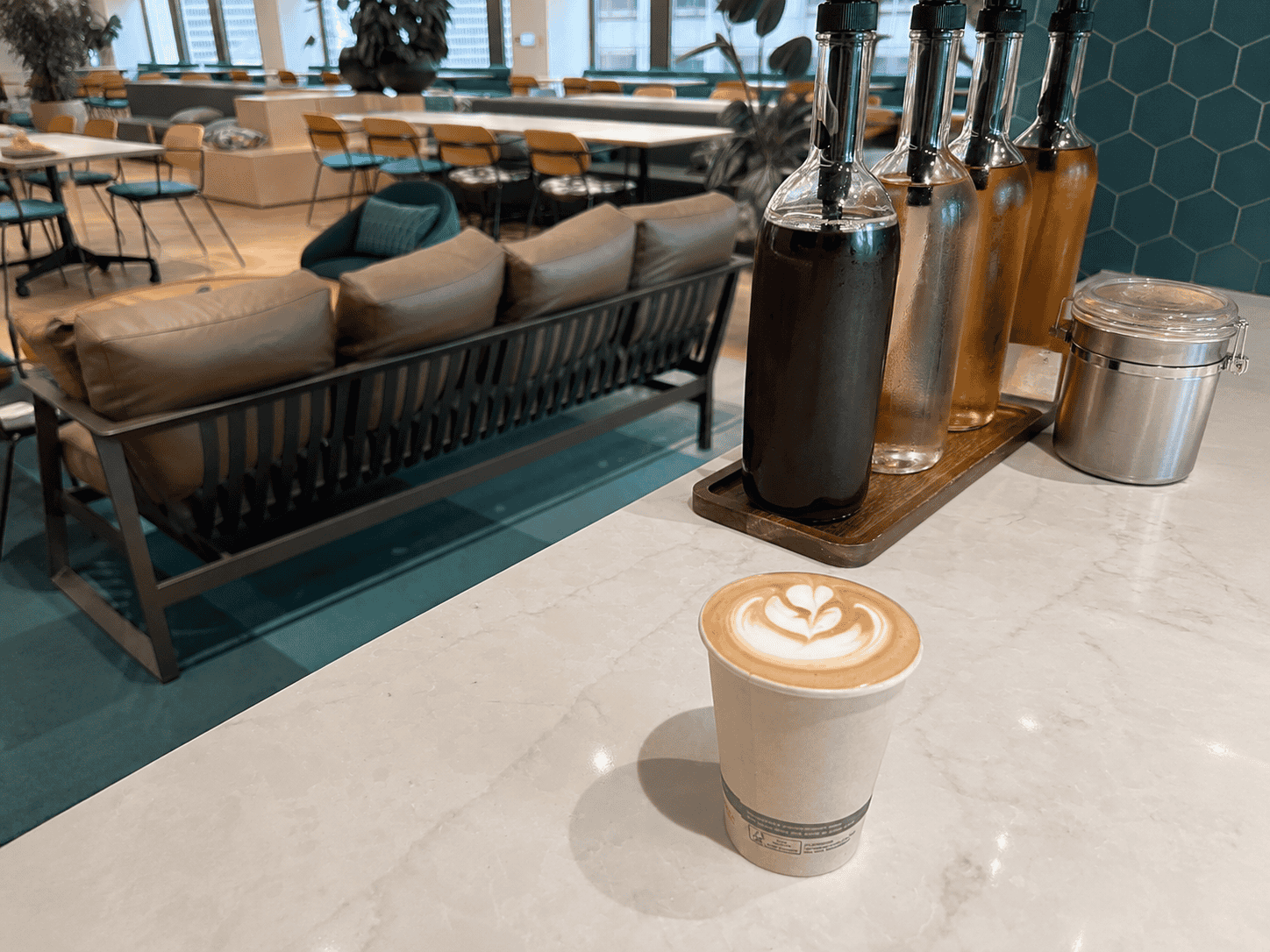 Espresso Station latte with rosetta art on a counter in a teal coworking office lounge