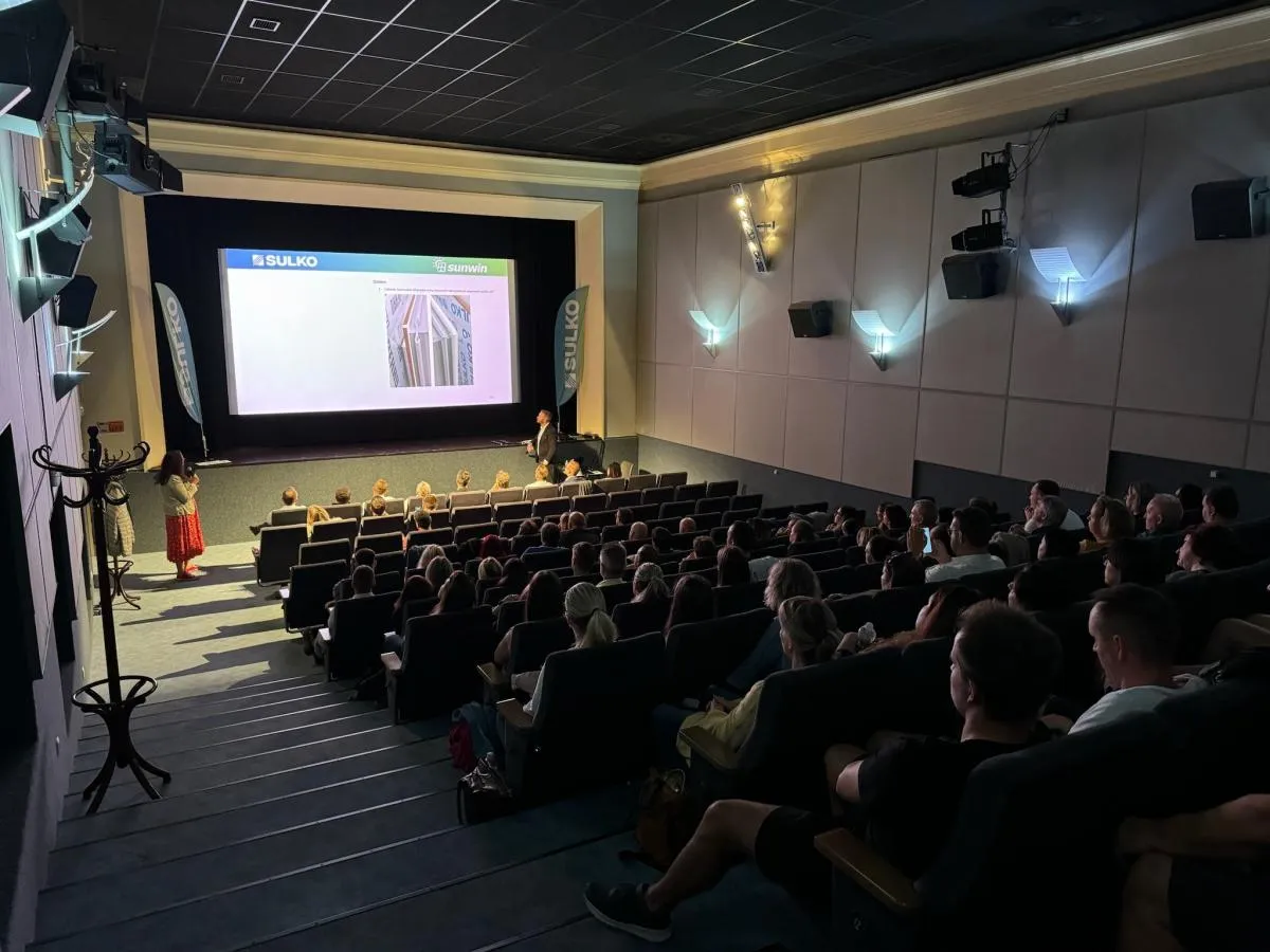 Obchodní tým sleduje prezentaci na velkém plátně v kině během firemního setkání.