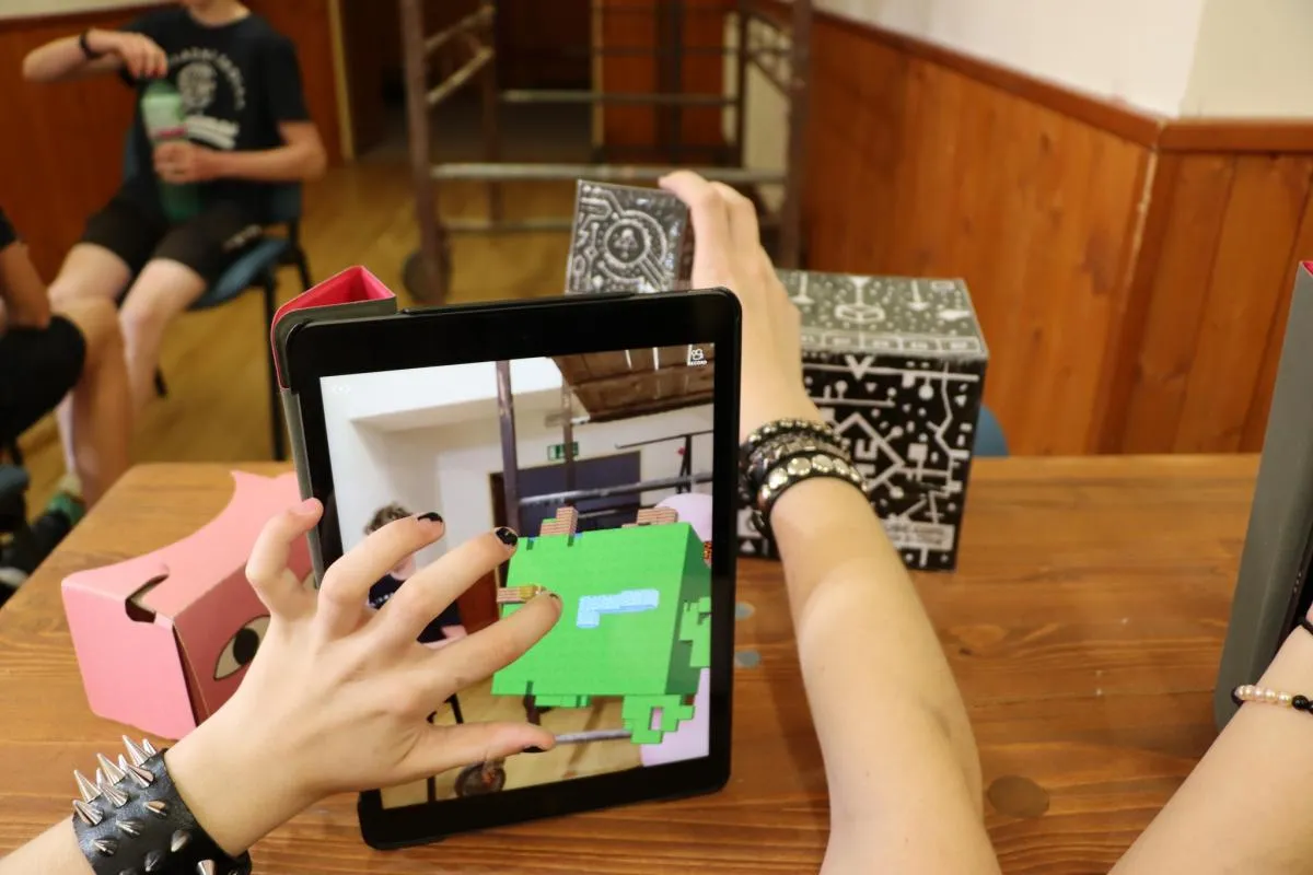 Dítě používá tablet s rozšířenou realitou během technologického workshopu.