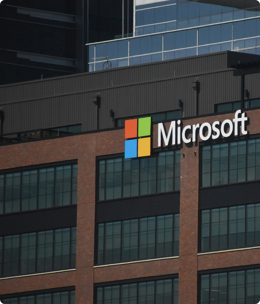 Logotipo de Microsoft en la fachada de un edificio de oficinas con ventanas grandes.