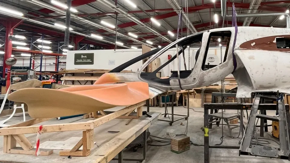 Side view of the partially assembled Doroni aircraft prototype suspended in a workshop, with its cockpit structure exposed and aerodynamic body panels in progress.
