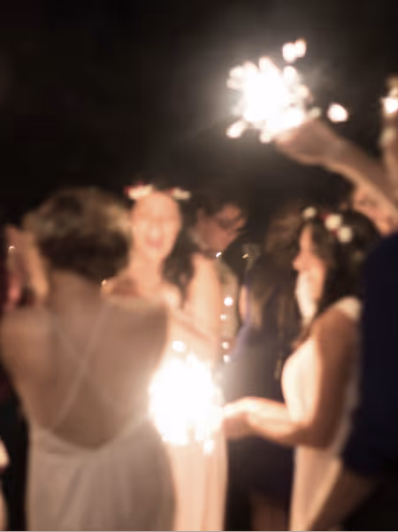 Blurry image of people holding sparklers at a nighttime celebration.
