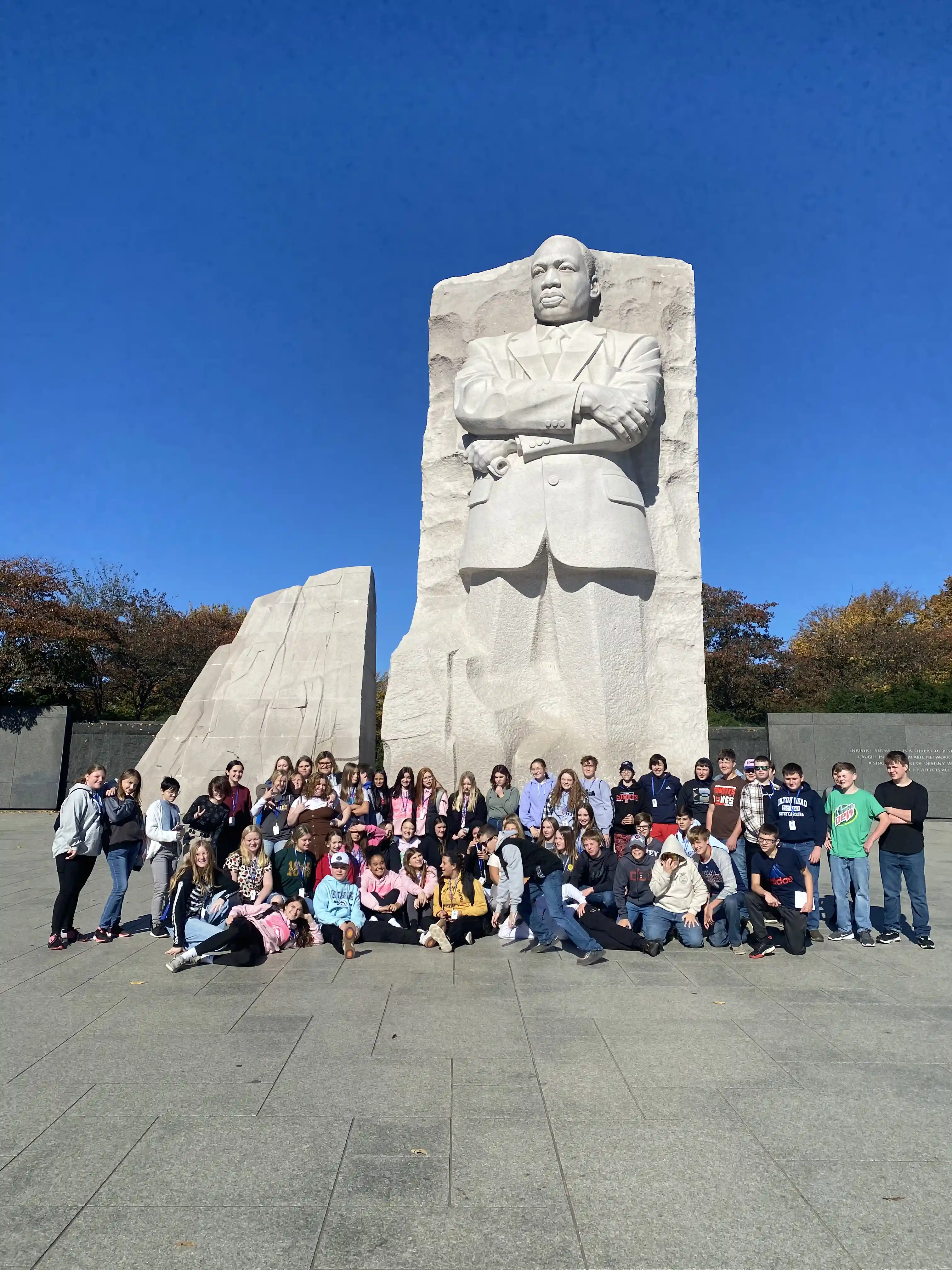 Individual wearing a red hat stands before a majestic waterfall tumbling down a rocky cliff amidst misty surroundings