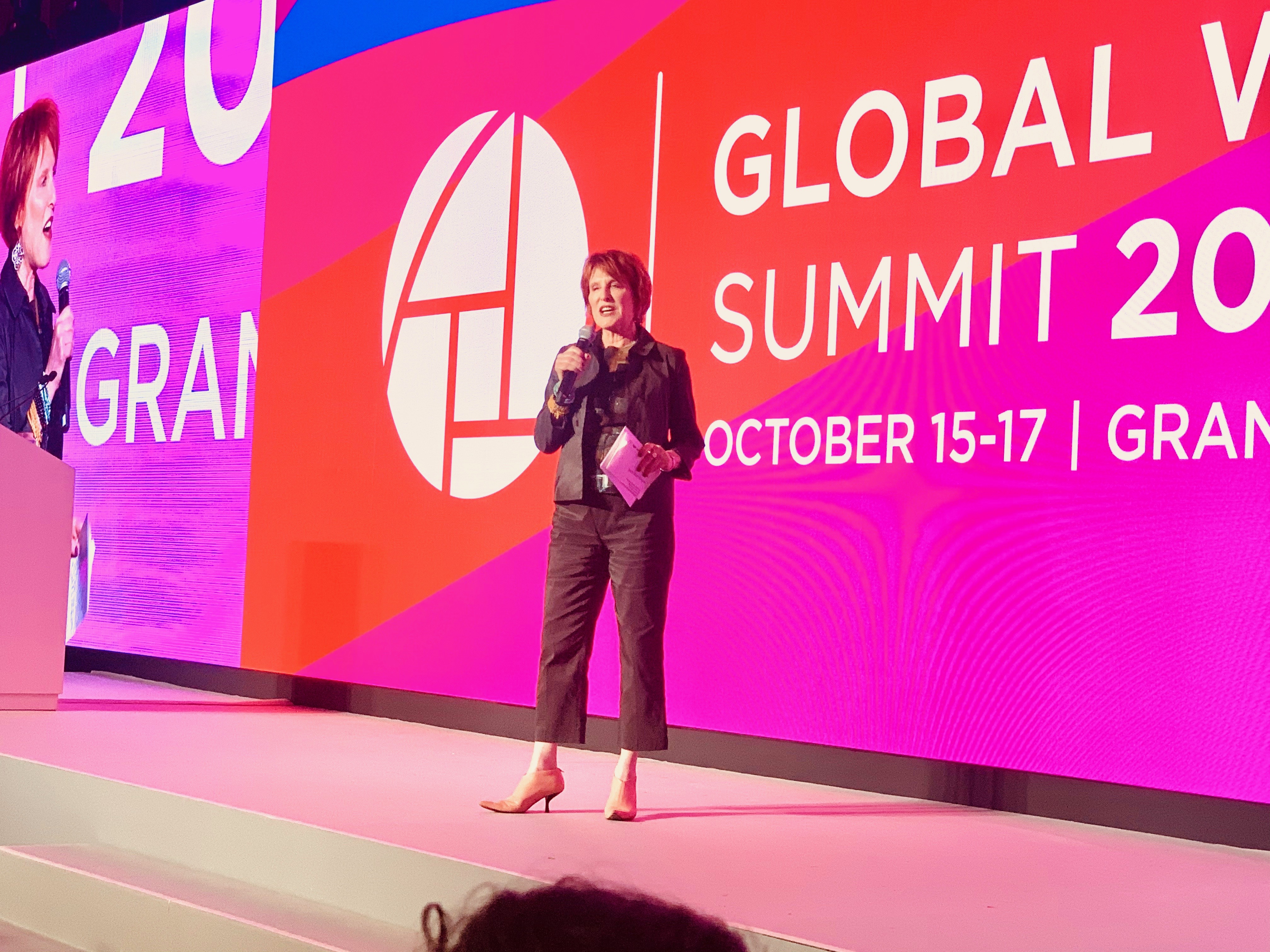 Woman standing on stage with pink background.