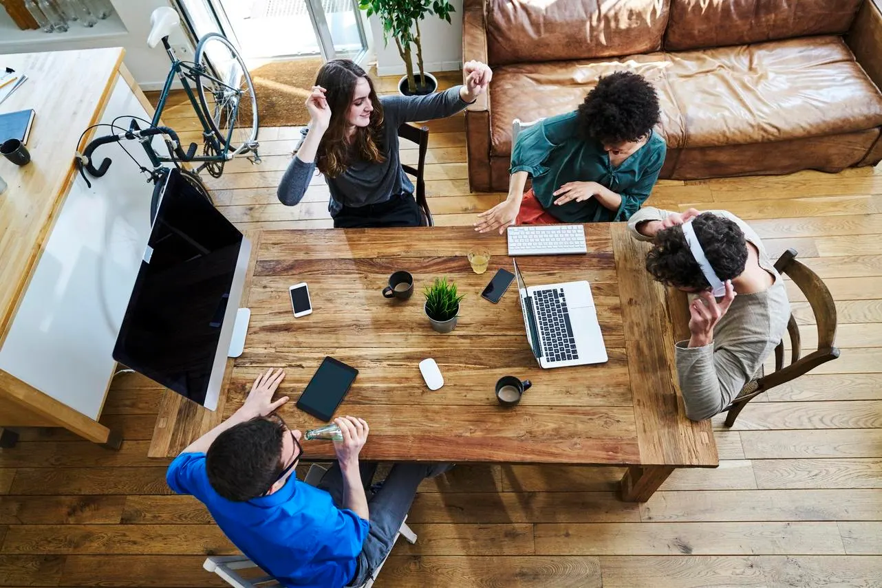 Group of adults working around a desk listening to music