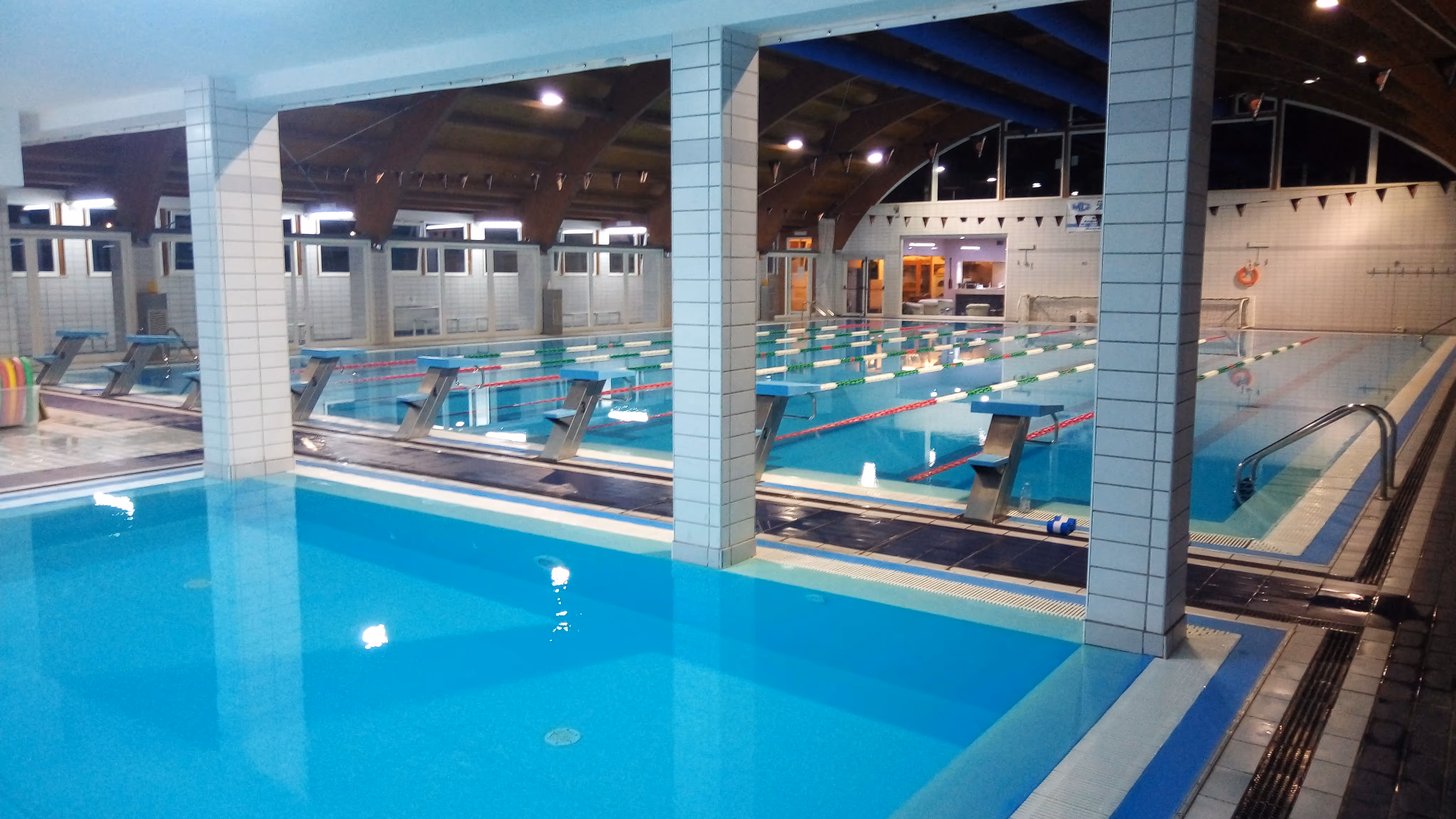 Una piscina coperta con una vasca per nuoto suddivisa in corsie e un ristretto spazio per bambini.