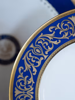 Close-up of a white ceramic plate with a decorative blue and gold ornate border.