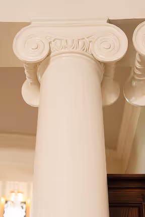 Close-up of a white Ionic architectural column with scroll-shaped volutes on the capital.