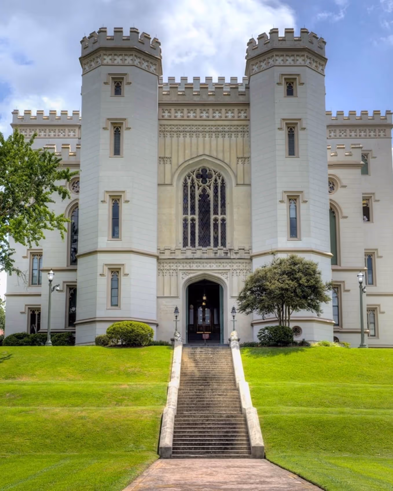 Front view of a white castle-like building with two round towers and a large staircase leading to the entrance.