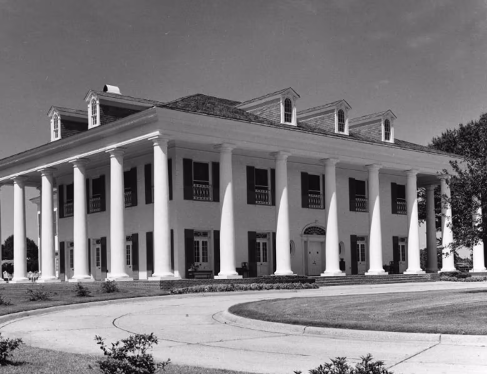 Large colonial-style building with tall white columns and dormer windows under a clear sky.