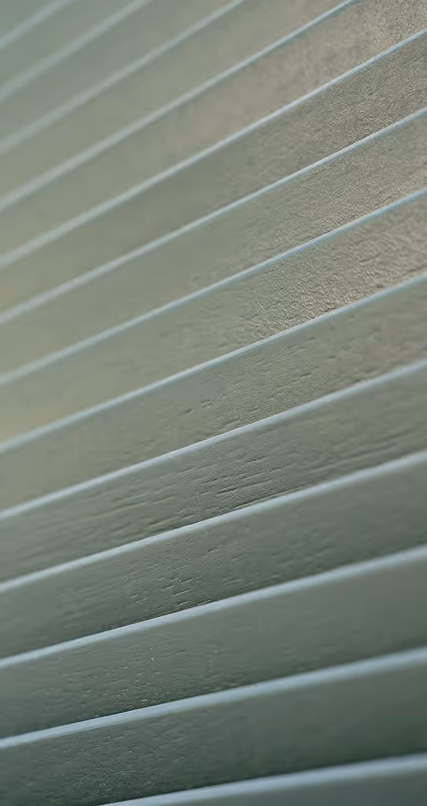 Close-up of angled horizontal wooden slats painted in muted green.