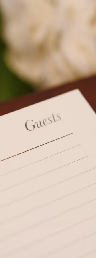 Blank guest sign-in sheet with lined entries and white flowers blurred in the background.