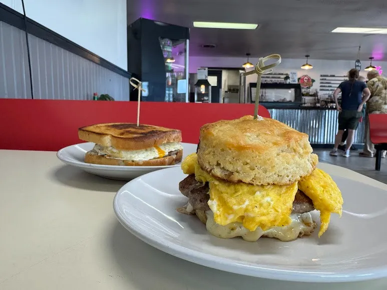Two plates featuring breakfast sandwiches, each with layers of egg, cheese, and meat, arranged appetizingly.