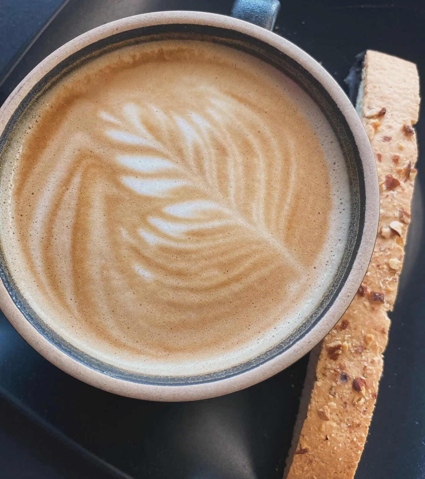 A cup of coffee featuring a decorative leaf design on the frothy surface.
