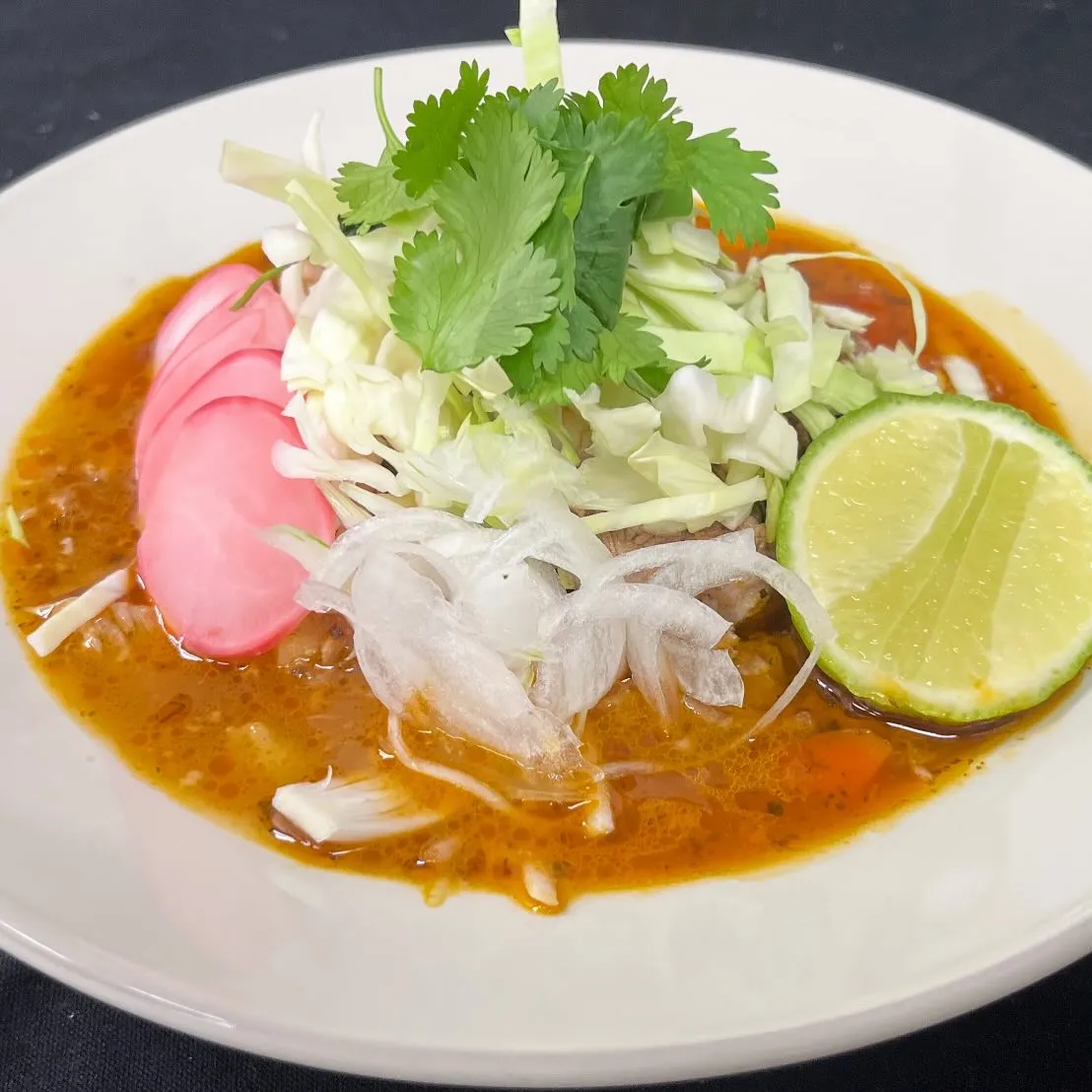 A plate featuring a serving of meat, colorful vegetables, and a wedge of lime for garnish.