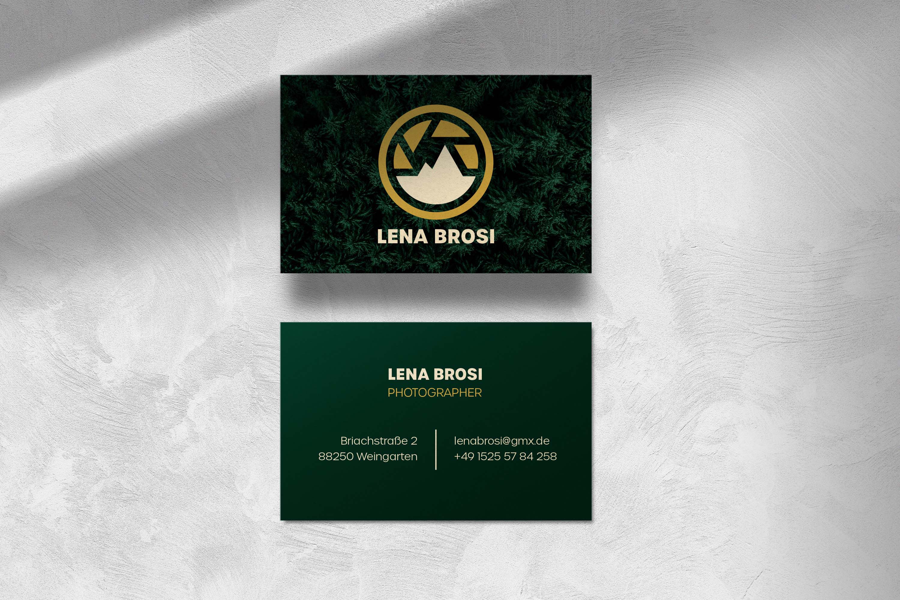 Business card for Lena Brosi, photographer, with a dark green background and gold logo featuring a mountain and camera shutter design; contact details include address, email, and phone number.