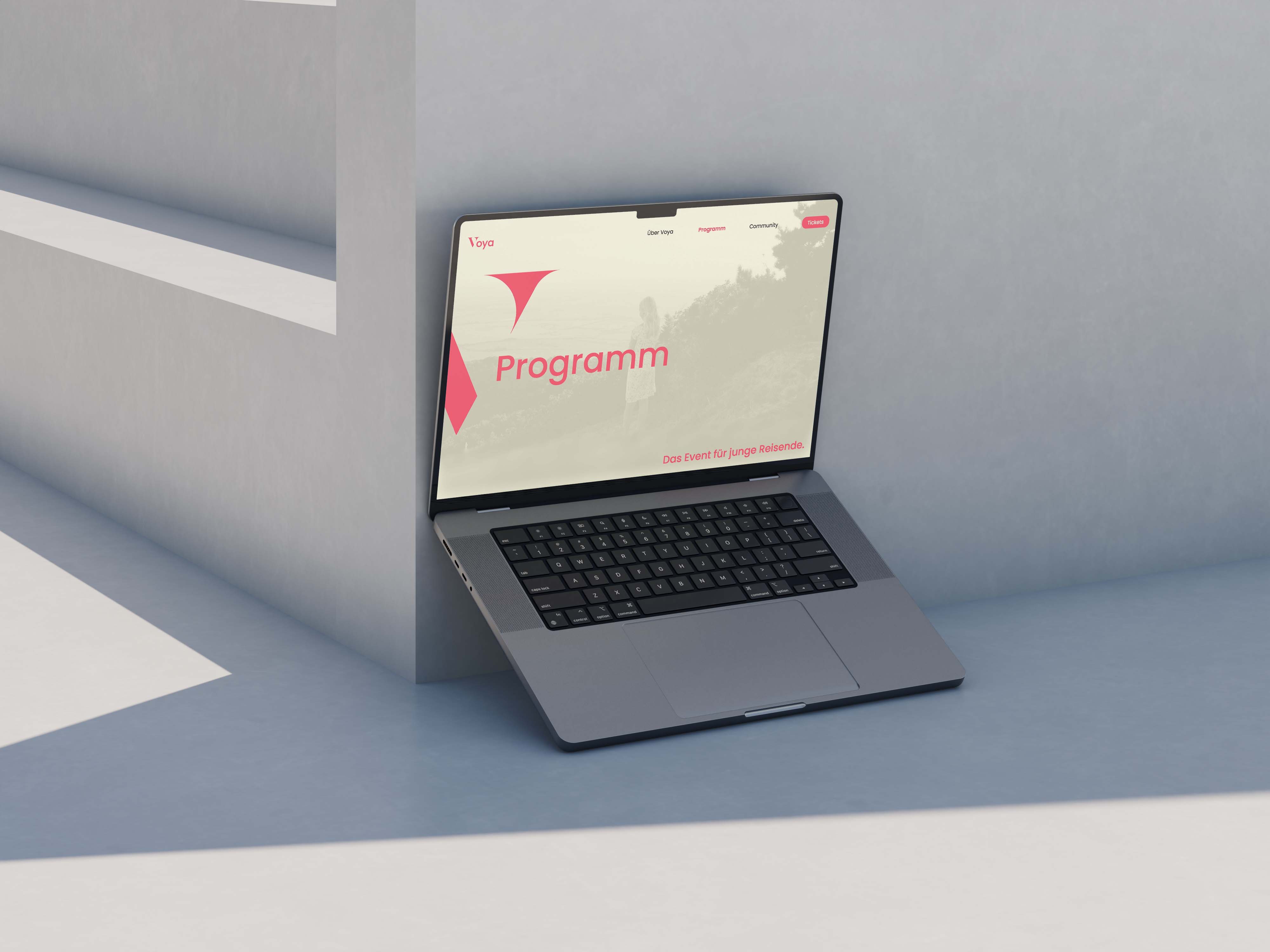 Open laptop leaning against a light gray wall showing a website homepage with the headline 'Programm' and a navigation bar including Home, Programm, Community, and Tickets.