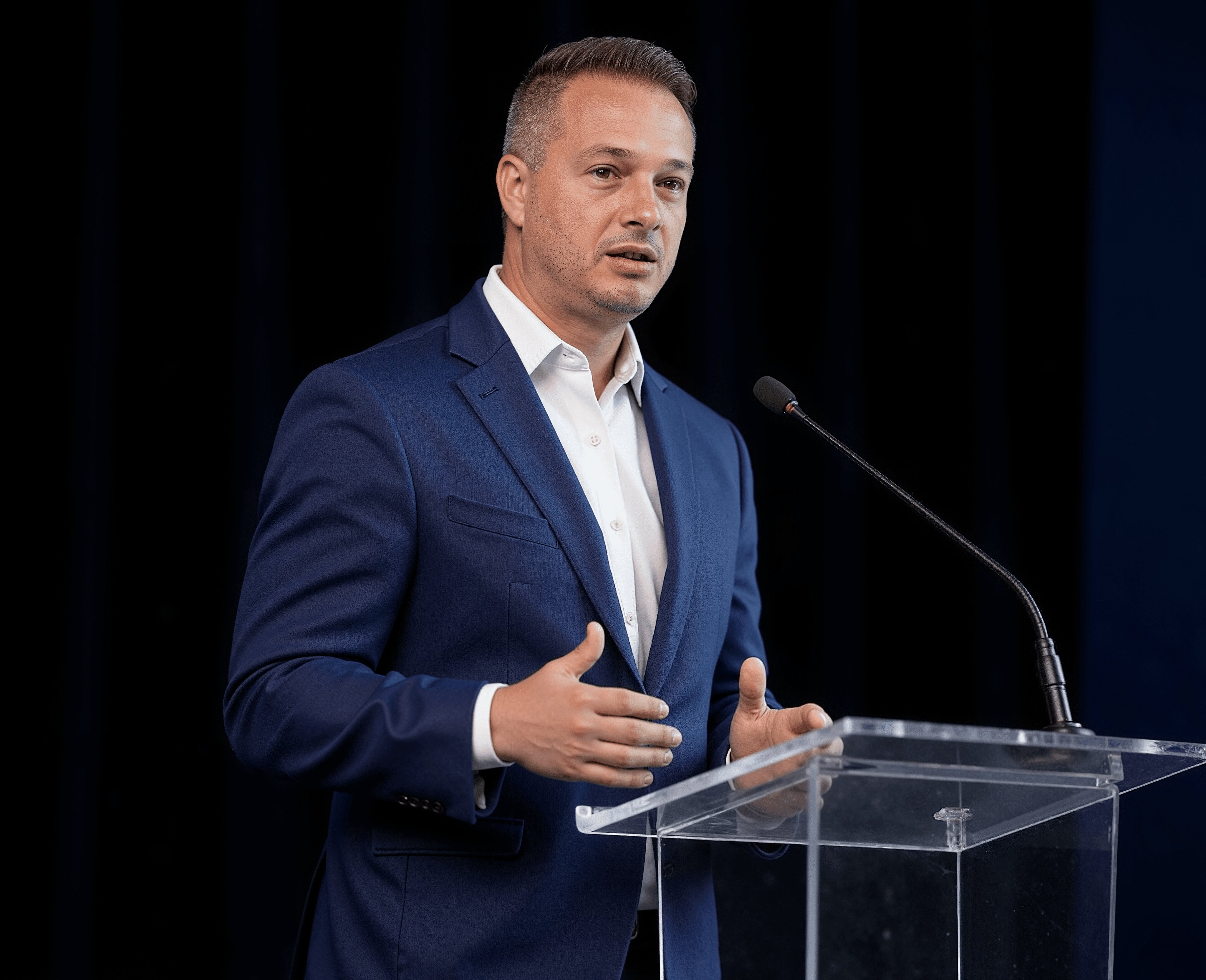 A picture os Dewald in suits, presenting at a panel at an event