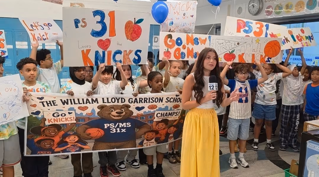 News reporter interviews PS MS 31x students holding Go Knicks signs