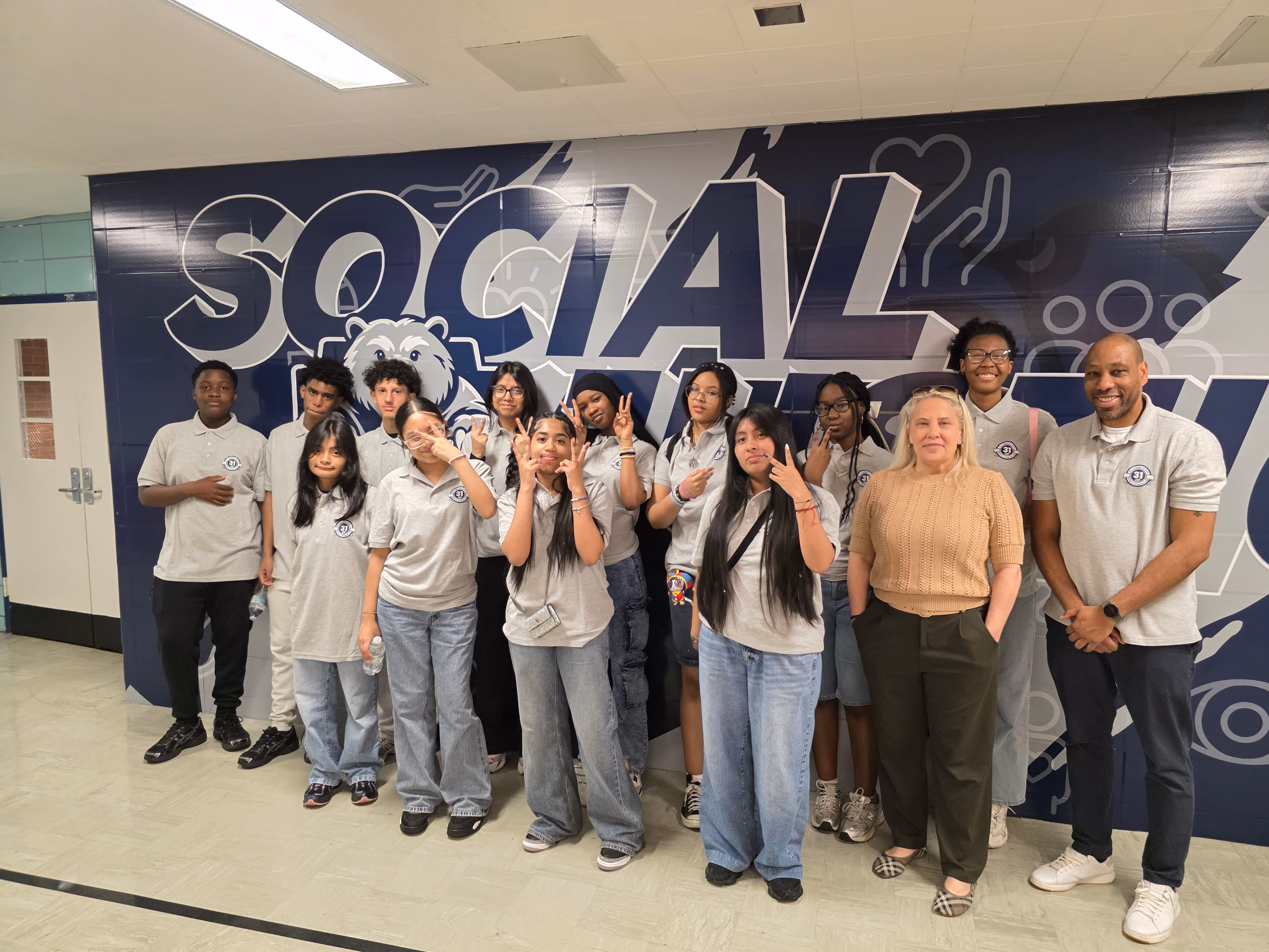 Students and staff posing in front of school Social Emotional mural
