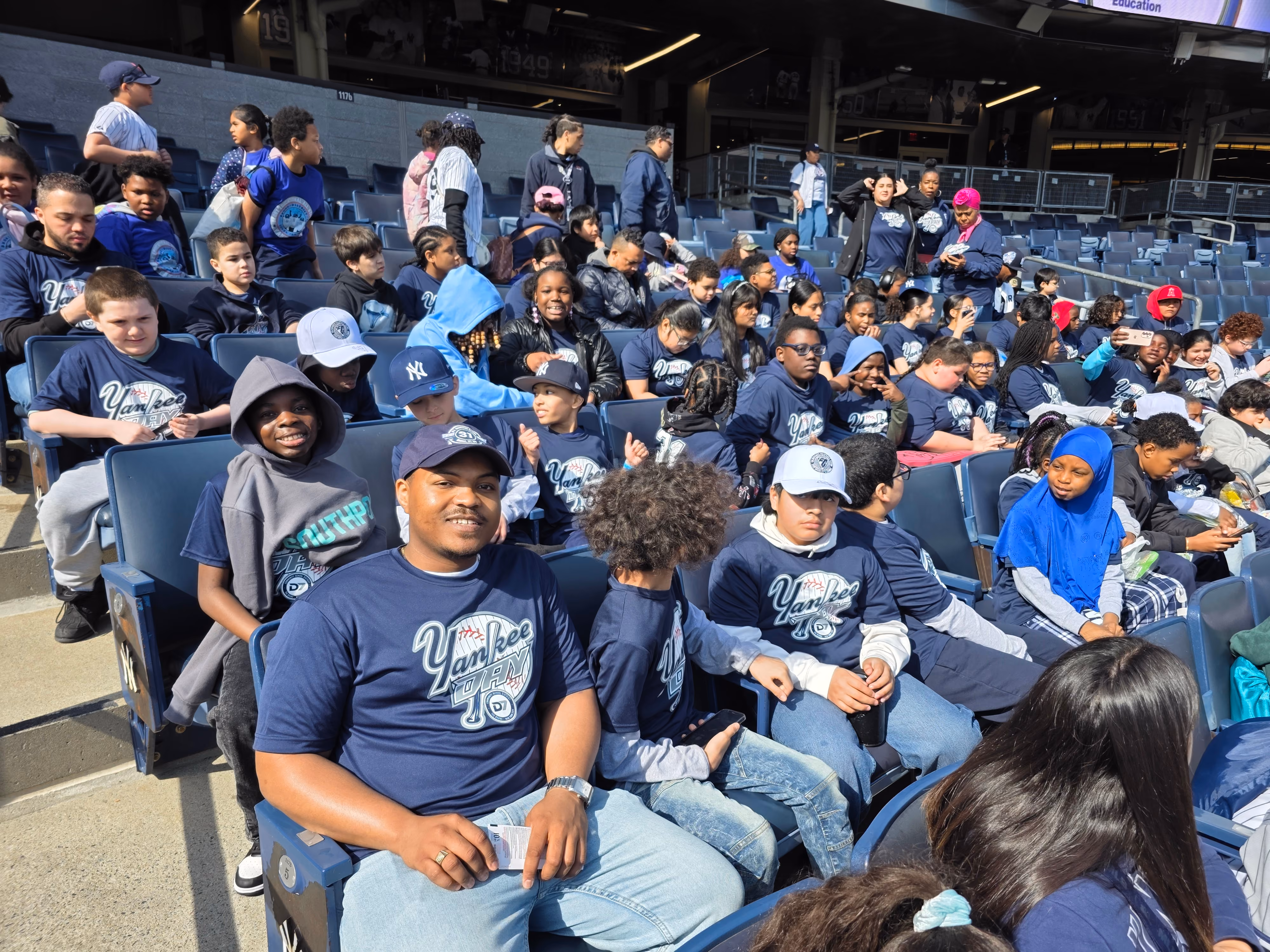 Students and chaperones in Yankee shirts at a stadium field trip