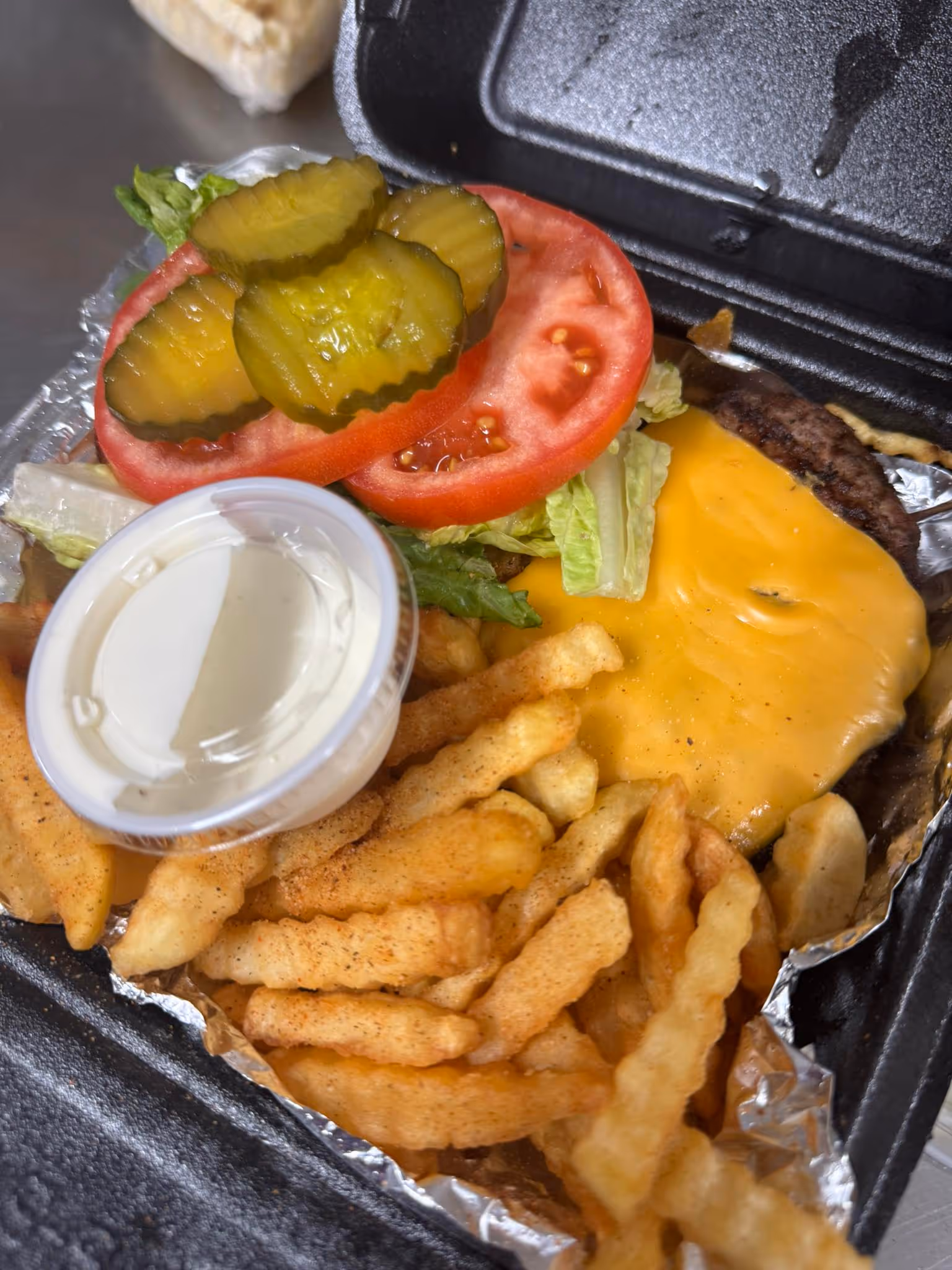 A cheeseburger with lettuce and tomato on a paper plate.
