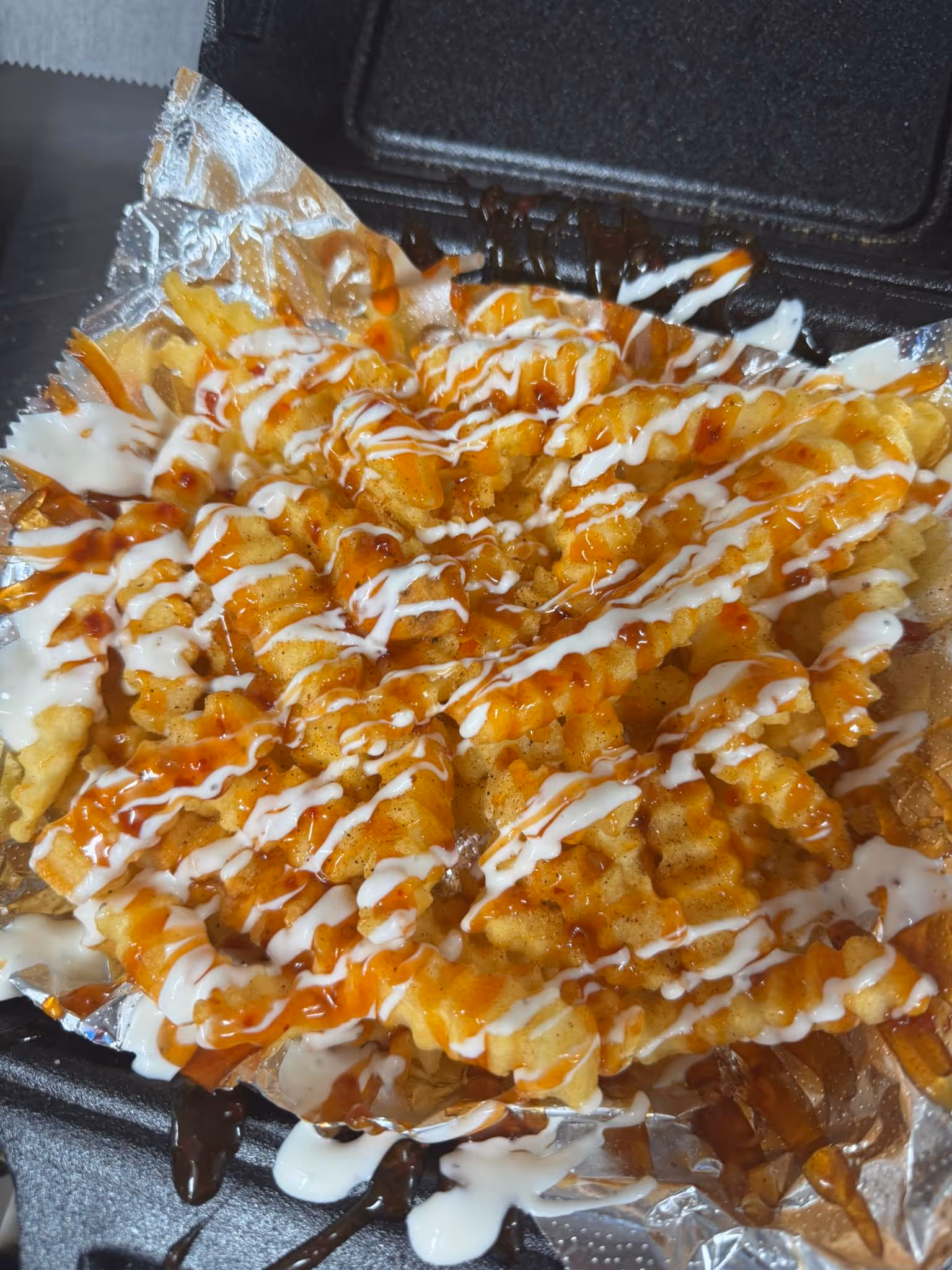 A basket of fries with ketchup and cheese on top.