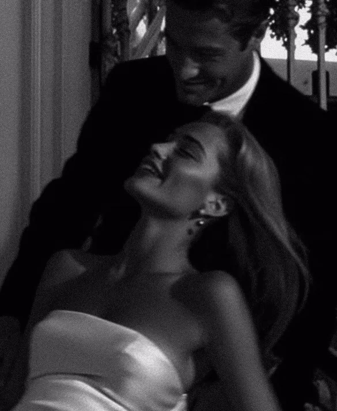 Black and white photo of a couple dancing closely, the woman in a strapless dress leaning back and smiling.