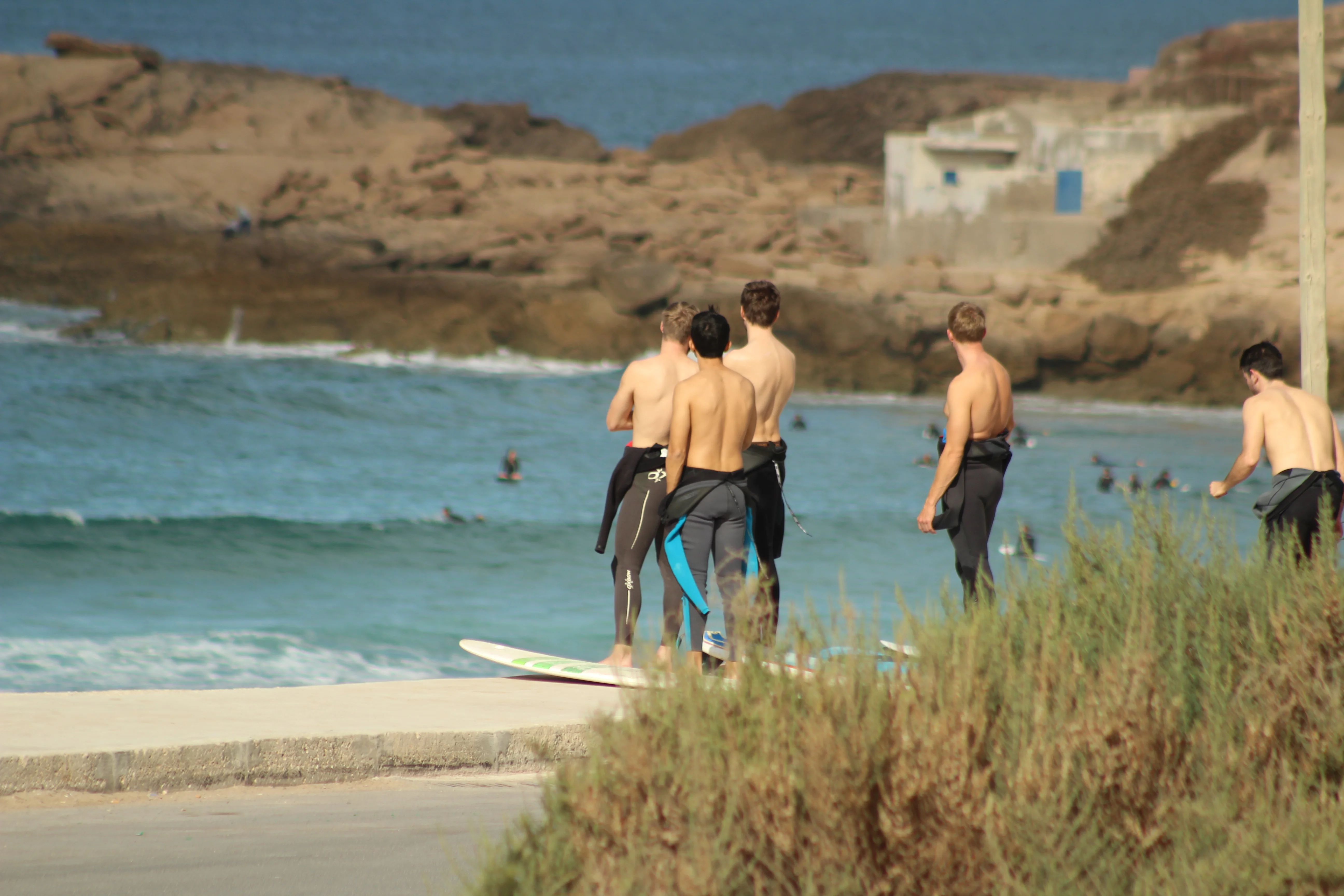 Two surfers paddling on a small wave, one on a yellow board and one on a blue board.
