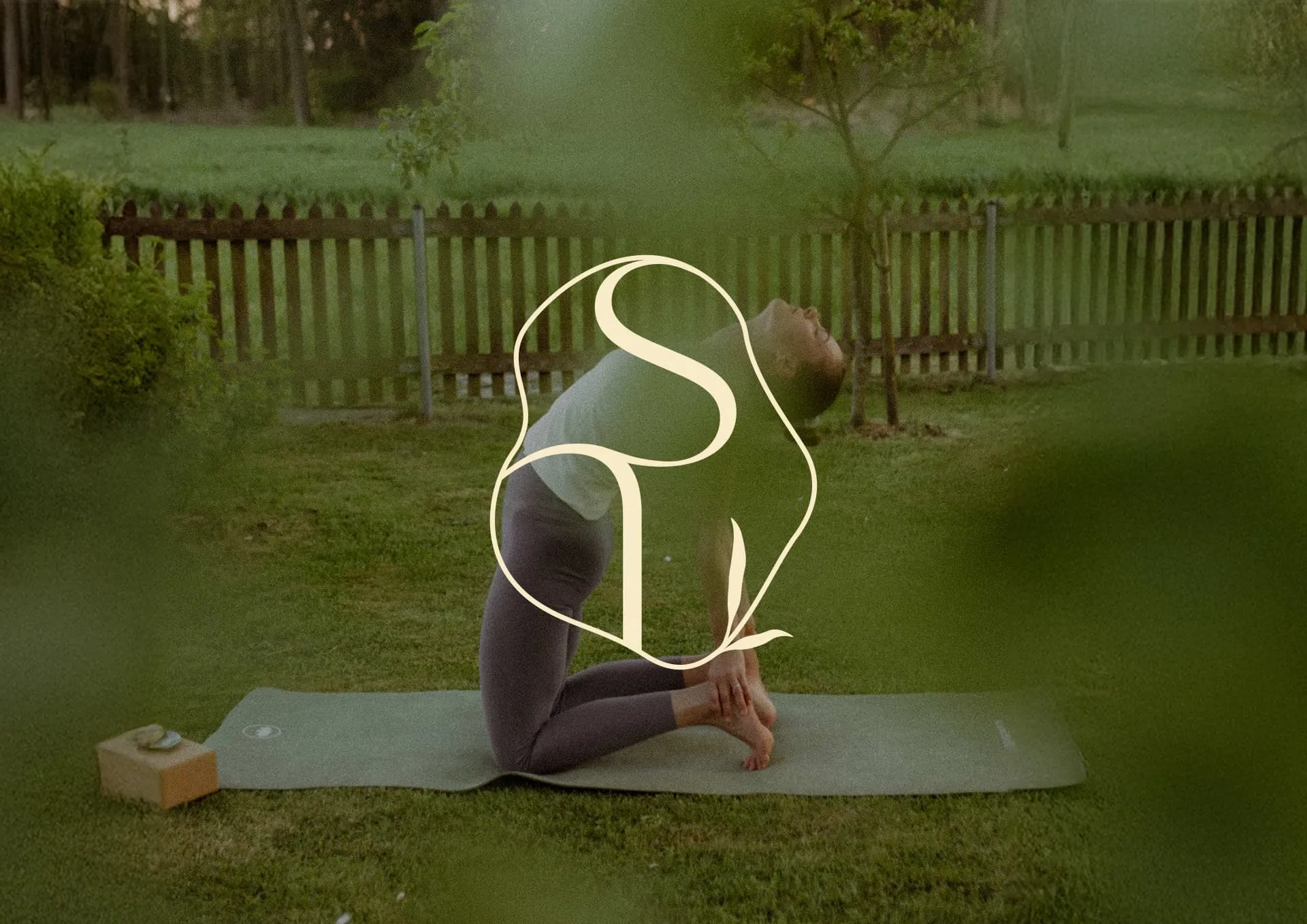 Frau macht Kamel-Yoga-Pose kniend auf einer Matte in einem Garten mit Holzzaun im Hintergrund.