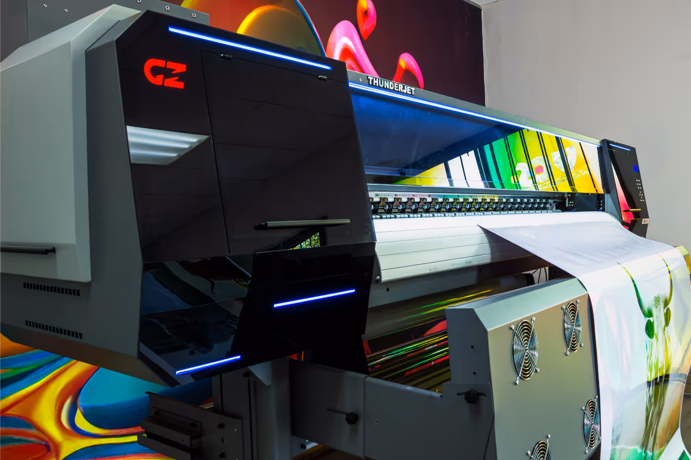 Large industrial digital printer producing a colorful printed banner with an image of a green bull.