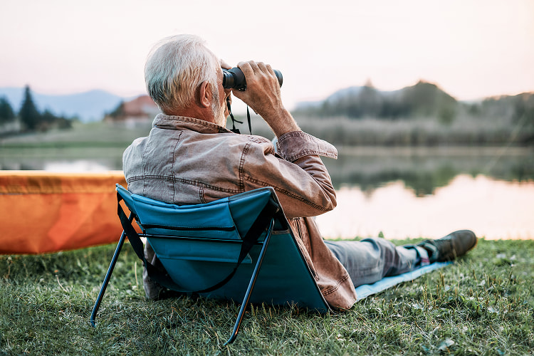 Retiree bird watching at a lake.