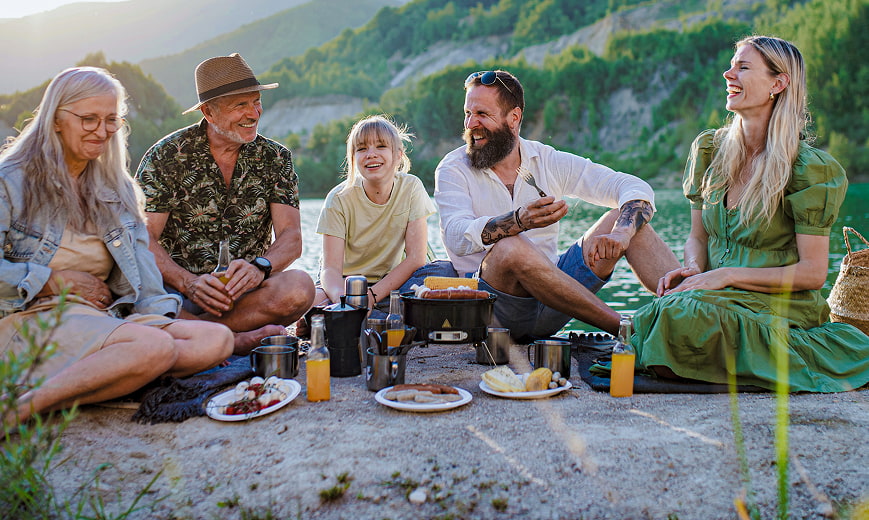Retirees and their family having breakfast on the beach next to a lake