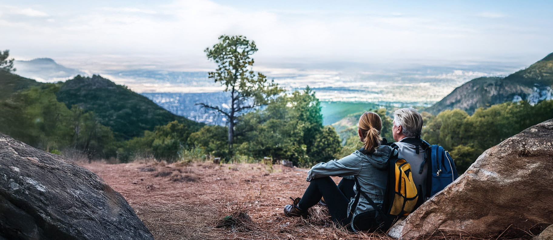 Retired couple resting on a hike through the mountains