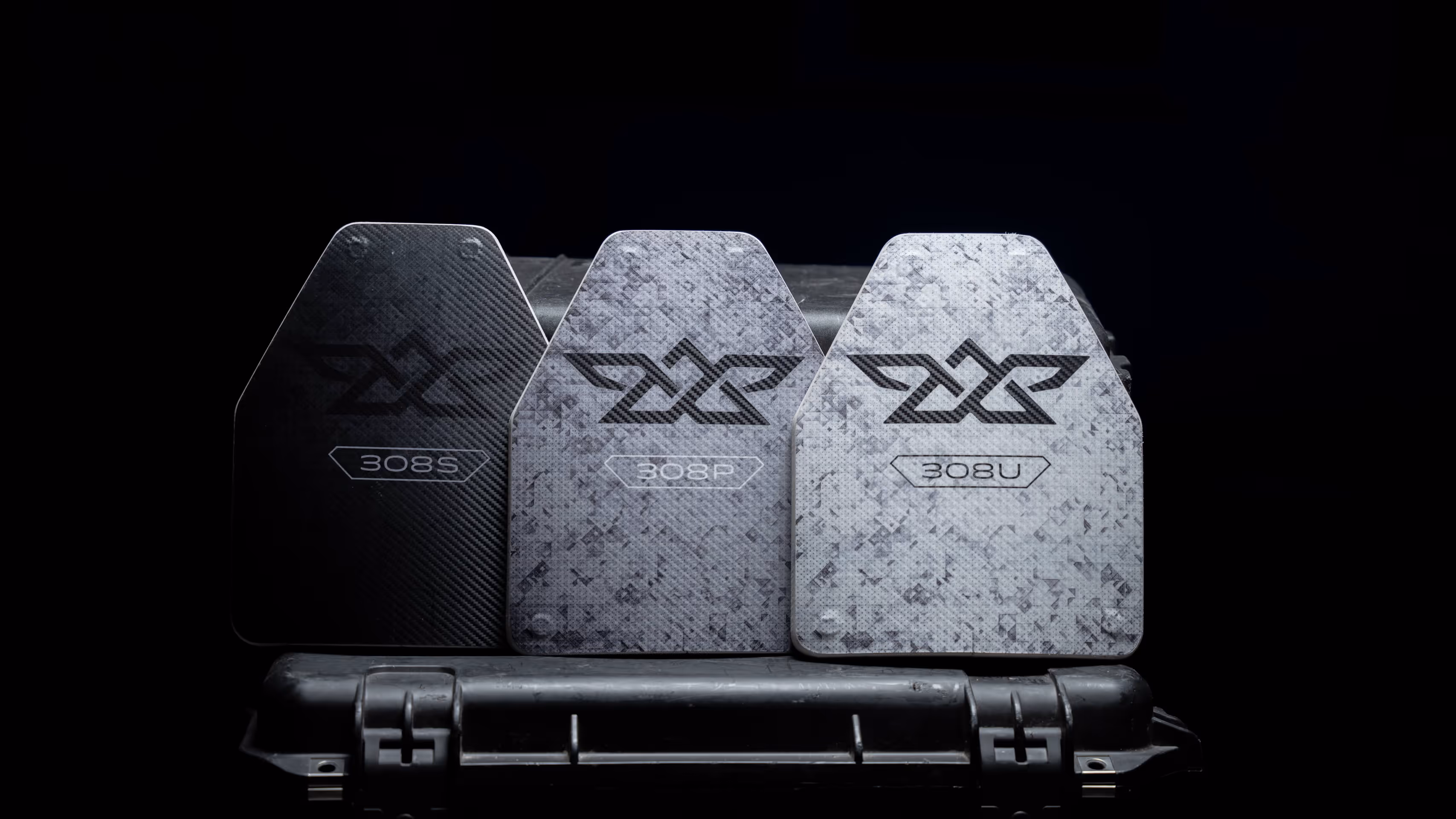 Three ballistic plates labeled 308S, 308P, and 308U arranged in front of a black case.