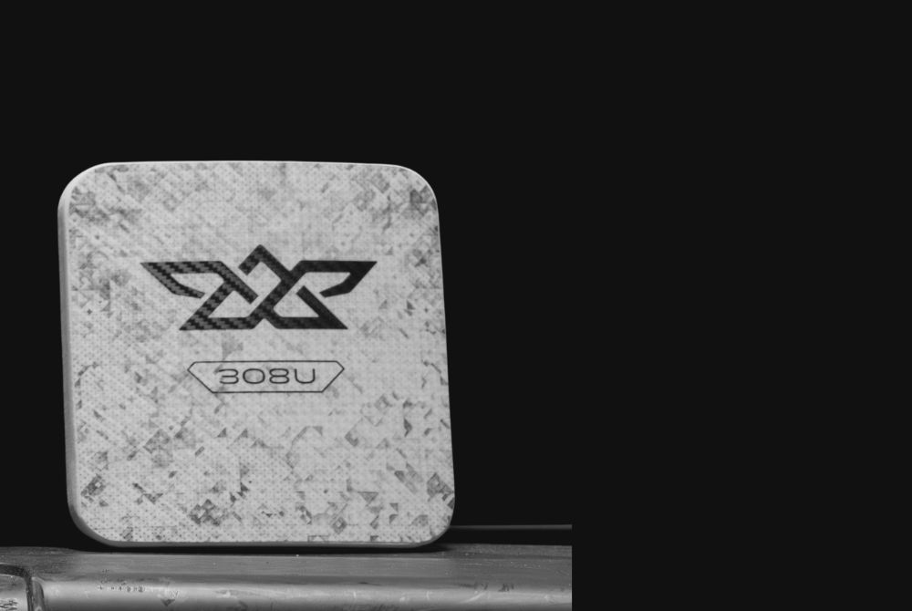 Square textured device with a logo and the text '308U' on its surface against a dark background.