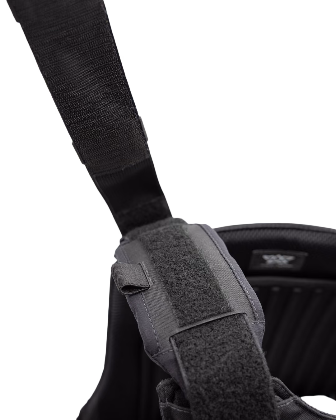 Close-up of black adjustable strap with Velcro fastening on padded harness or backpack.