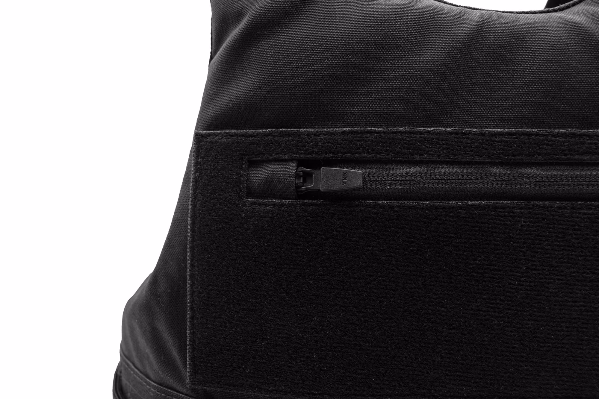 Close-up of a black fabric tactical vest with a zipper and Velcro panel.