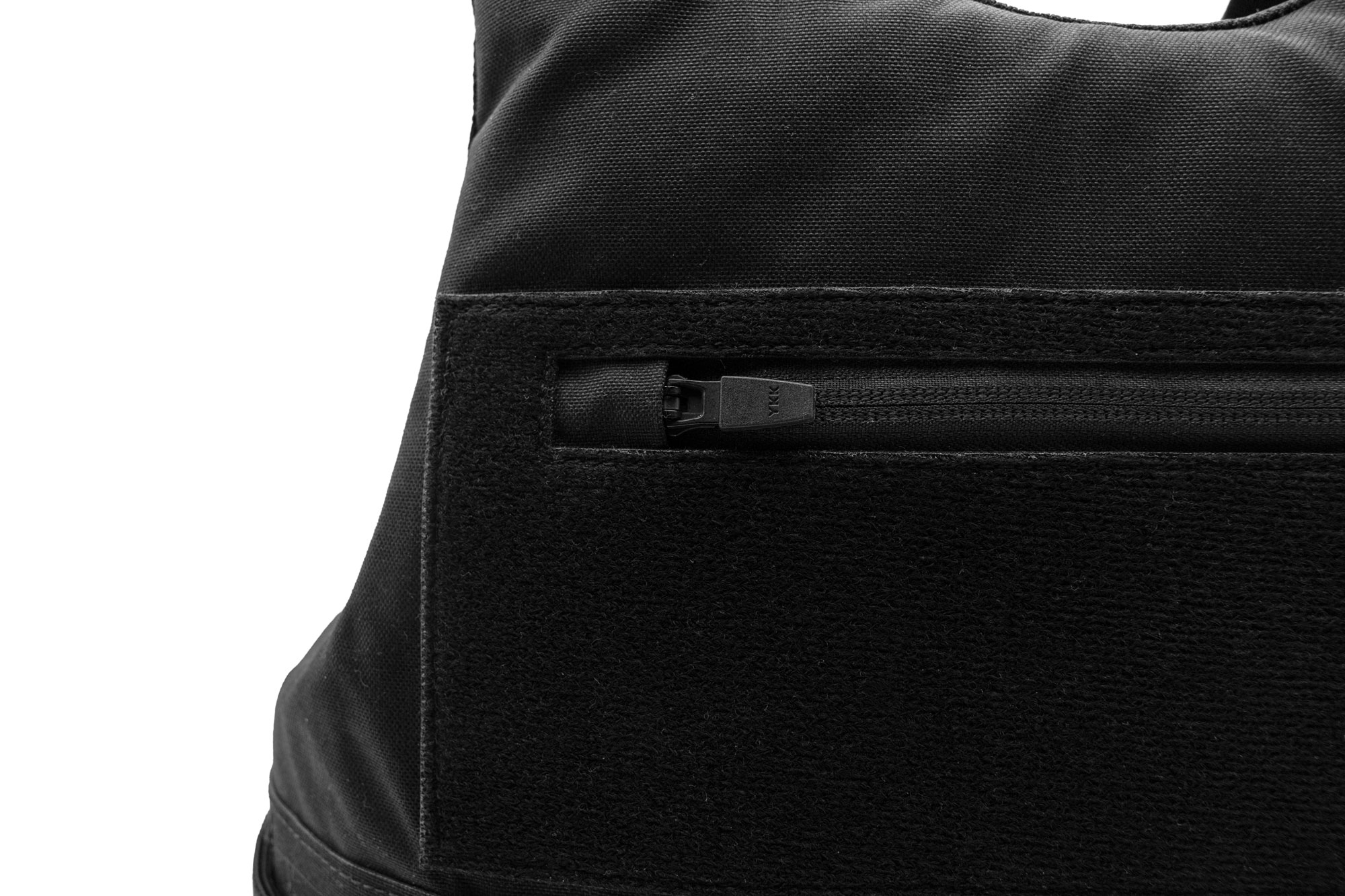 Close-up of a black fabric tactical vest with a zipper and Velcro panel.