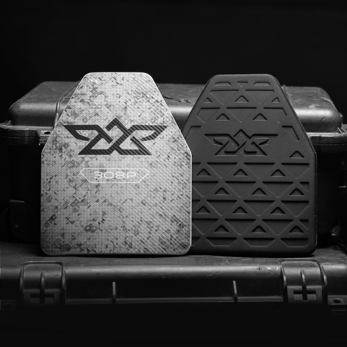 Two ballistic plates with logos, one camouflaged marked 308P and one plain black, on a black case.