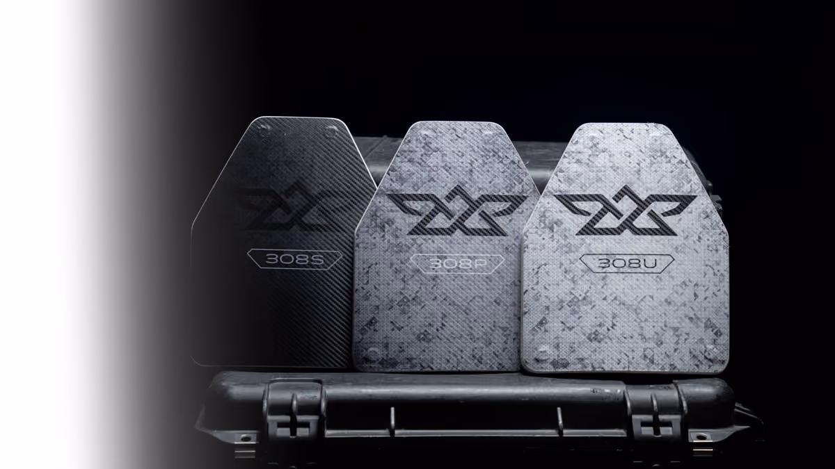Three ballistic plates labeled 308S, 308P, 308U resting on a hard case against a black background.