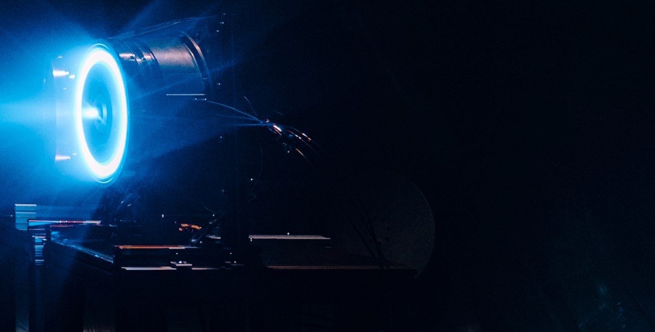 Engineers working inside the K2 Space manufacturing facility, assembling satellite components behind large glass panels